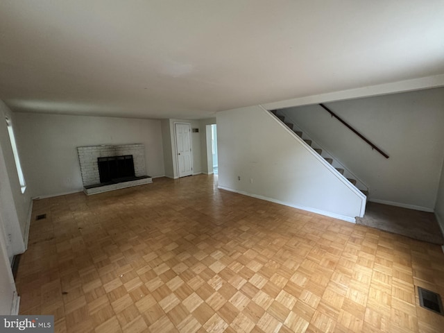 unfurnished living room with light parquet floors and a brick fireplace