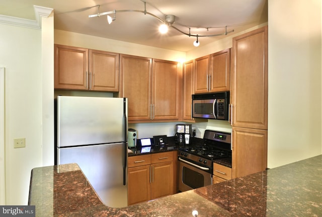 kitchen featuring dark stone countertops, appliances with stainless steel finishes, and rail lighting