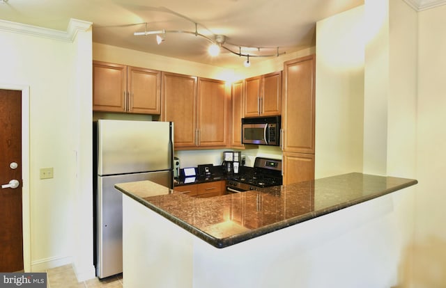 kitchen featuring crown molding, dark stone countertops, stainless steel appliances, kitchen peninsula, and rail lighting