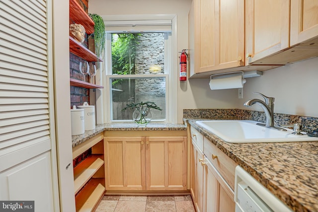 kitchen featuring light stone countertops, sink, white dishwasher, and light brown cabinets