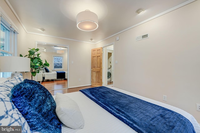 bedroom with ornamental molding, washer / dryer, and hardwood / wood-style flooring