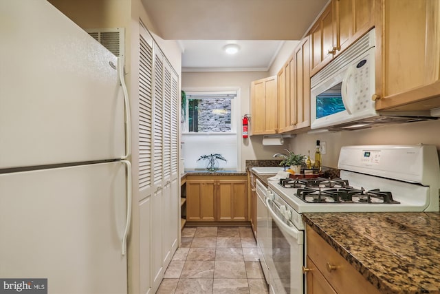 kitchen featuring dark stone countertops, sink, and white appliances