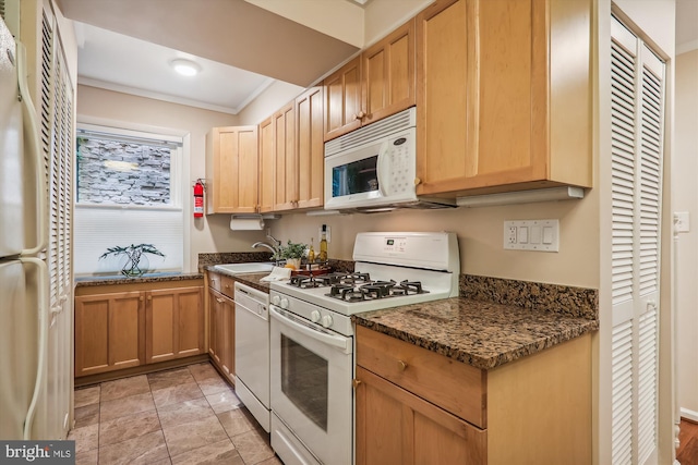 kitchen featuring dark stone countertops, ornamental molding, sink, and white appliances