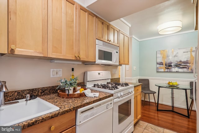 kitchen featuring dark stone counters, sink, white appliances, light brown cabinets, and crown molding