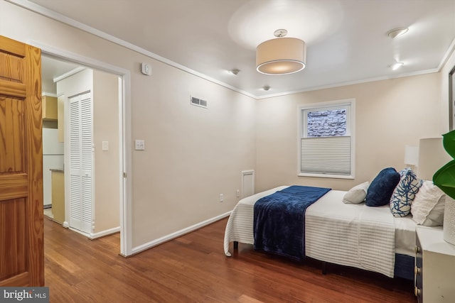 bedroom with dark hardwood / wood-style floors, ornamental molding, and white fridge