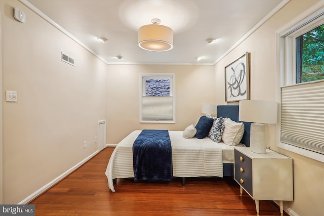 bedroom with crown molding and dark wood-type flooring