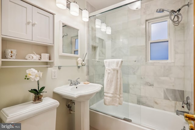 bathroom featuring toilet and combined bath / shower with glass door