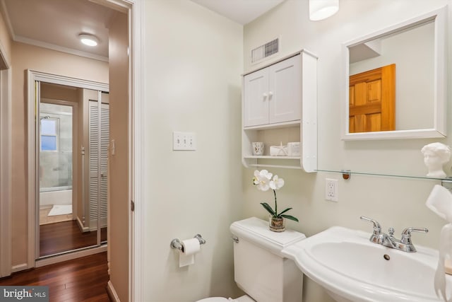 bathroom featuring ornamental molding, hardwood / wood-style flooring, sink, and toilet