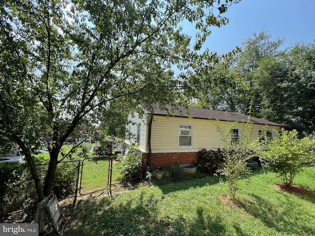 view of home's exterior with a gate, fence, brick siding, and a yard