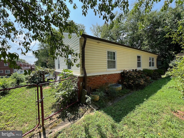 view of side of home with brick siding, a lawn, and fence