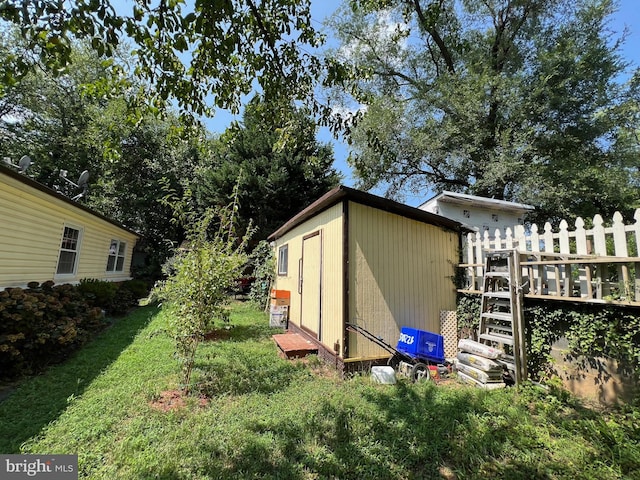 view of home's exterior with an outbuilding, a deck, a storage shed, and a yard