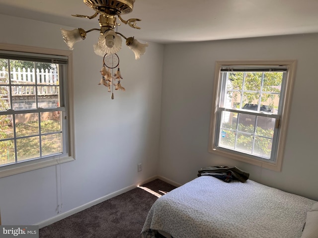 bedroom featuring dark carpet and baseboards