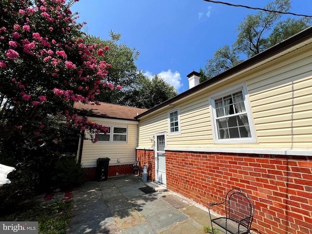 view of property exterior featuring a chimney and a patio