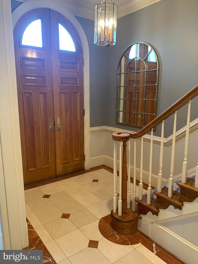 entryway with a chandelier, crown molding, and tile floors