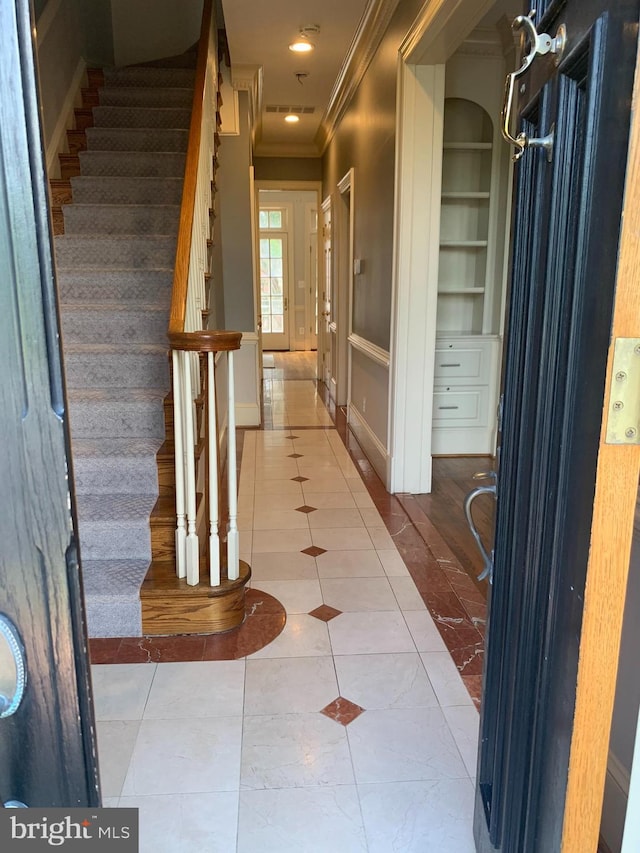 interior space featuring ornamental molding, built in shelves, and tile floors