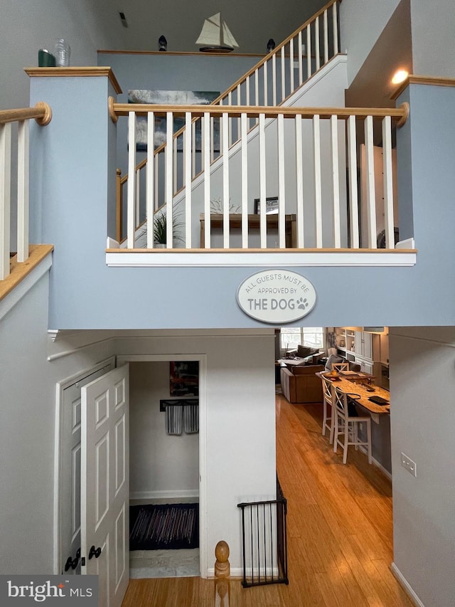 stairway with a towering ceiling and wood-type flooring