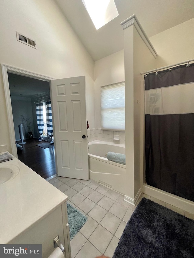 bathroom with tile patterned floors, vanity, independent shower and bath, and vaulted ceiling