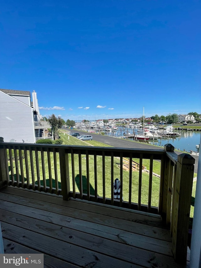 wooden deck with a water view and a lawn