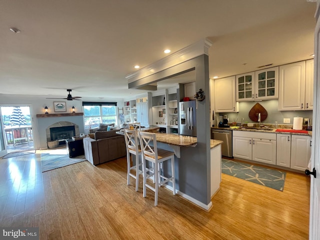 kitchen featuring a breakfast bar, white cabinets, ceiling fan, appliances with stainless steel finishes, and light hardwood / wood-style floors