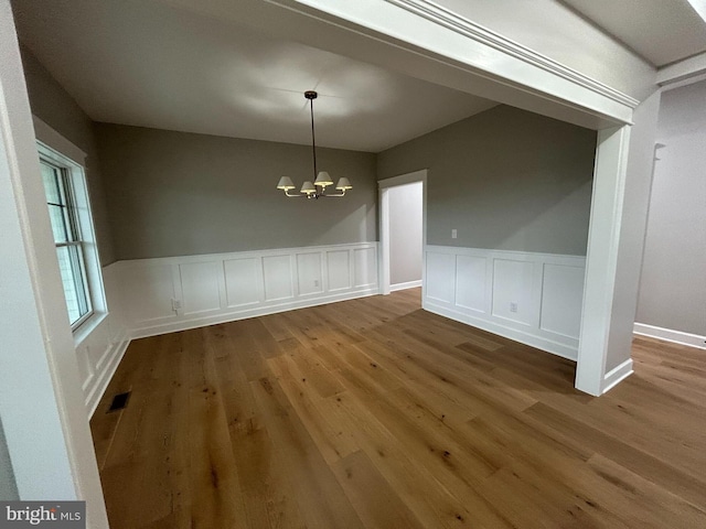 22430 Hummingbird Rd, Ellendale, DE 19941 - unfurnished dining area with a chandelier, wood finished floors, visible vents, and a wainscoted wall
