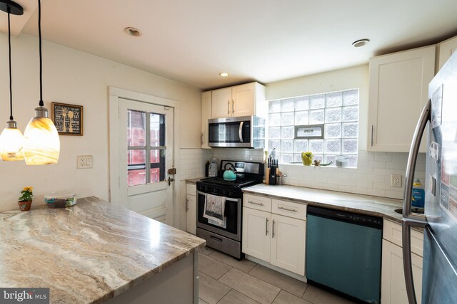 kitchen featuring stainless steel appliances, tasteful backsplash, hanging light fixtures, a healthy amount of sunlight, and white cabinets