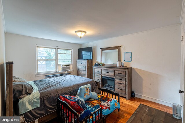 bedroom featuring cooling unit, light wood-style flooring, and baseboards