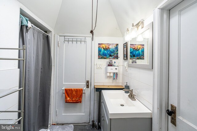 full bathroom with tile walls, vaulted ceiling, and vanity