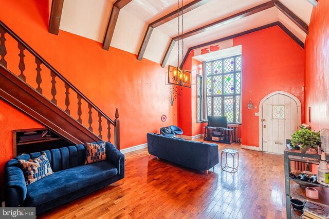 living area featuring high vaulted ceiling, wood finished floors, baseboards, stairs, and beam ceiling