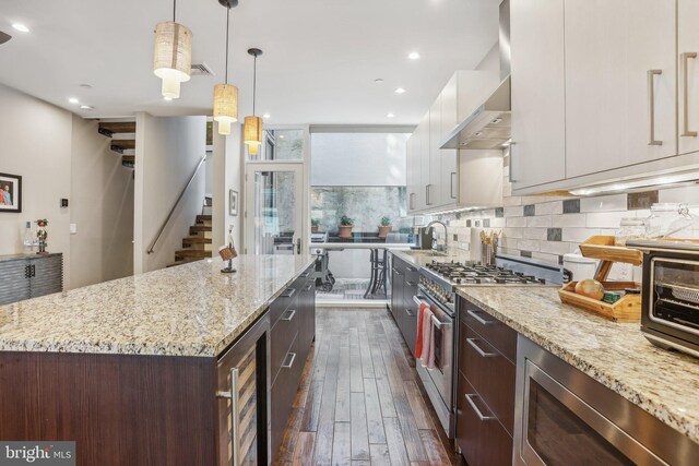 kitchen with white cabinetry, a center island, wall chimney exhaust hood, stainless steel appliances, and dark hardwood / wood-style floors