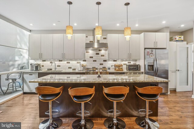 kitchen featuring sink, hanging light fixtures, stainless steel appliances, hardwood / wood-style floors, and a kitchen island