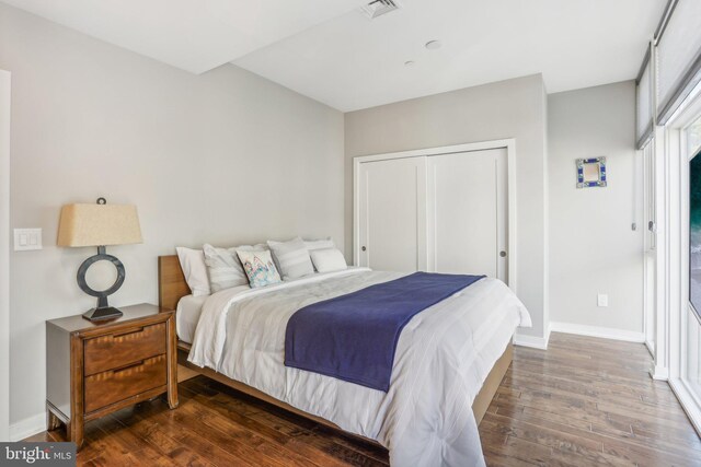 bedroom with dark hardwood / wood-style floors and a closet