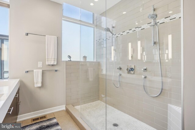 bathroom featuring tile patterned flooring, vanity, and tiled shower