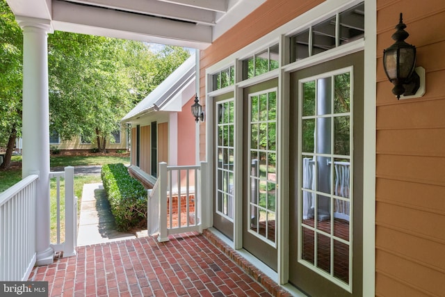 doorway featuring ornate columns, a wealth of natural light, and wood walls