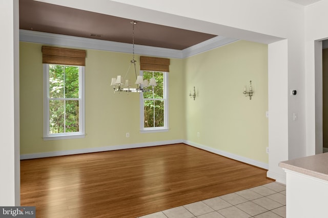 unfurnished dining area featuring crown molding, light hardwood / wood-style flooring, and a notable chandelier