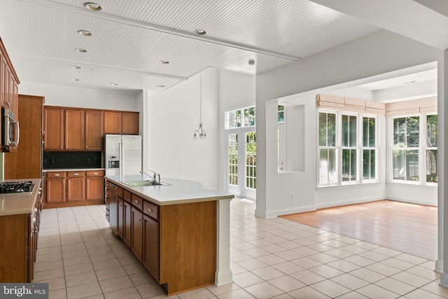 kitchen featuring light tile patterned flooring, appliances with stainless steel finishes, sink, and an island with sink