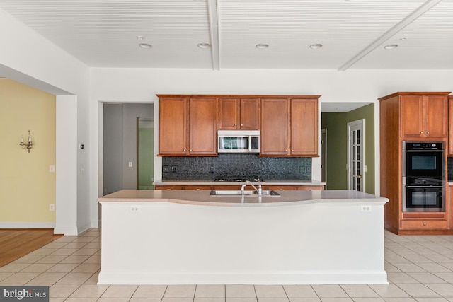 kitchen featuring a center island with sink, light tile patterned floors, stainless steel appliances, and sink