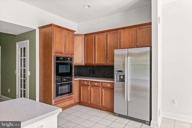 kitchen featuring light tile patterned floors, backsplash, and appliances with stainless steel finishes