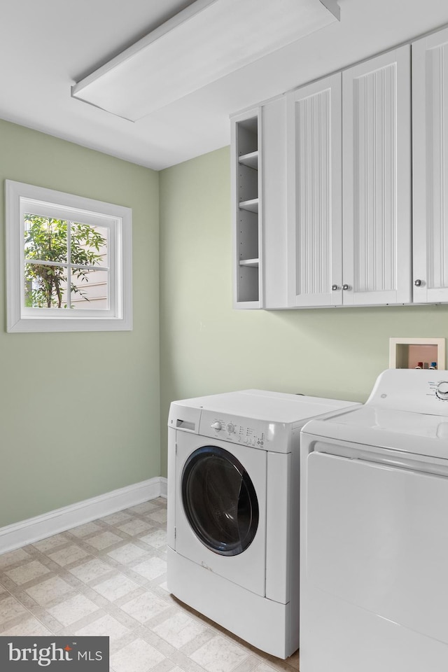 clothes washing area featuring separate washer and dryer and cabinets