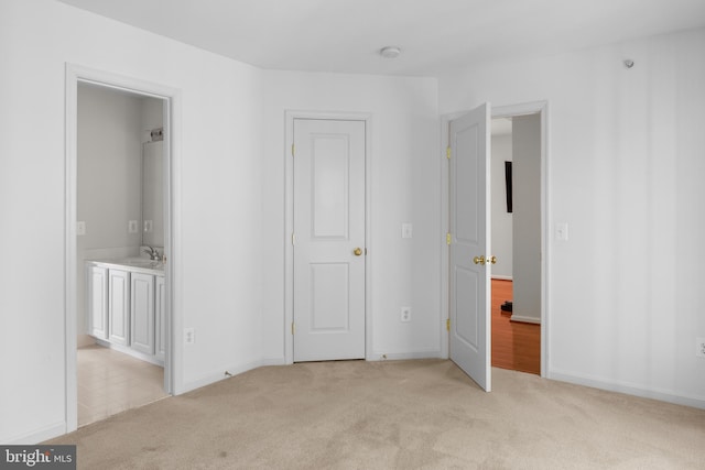 unfurnished bedroom with light colored carpet, sink, and ensuite bath