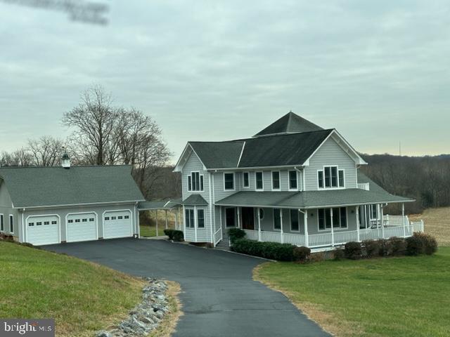 view of front of home featuring a garage, a front yard, and a porch