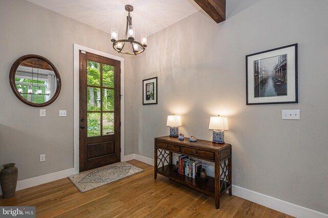 foyer entrance featuring a notable chandelier, beamed ceiling, and hardwood / wood-style floors