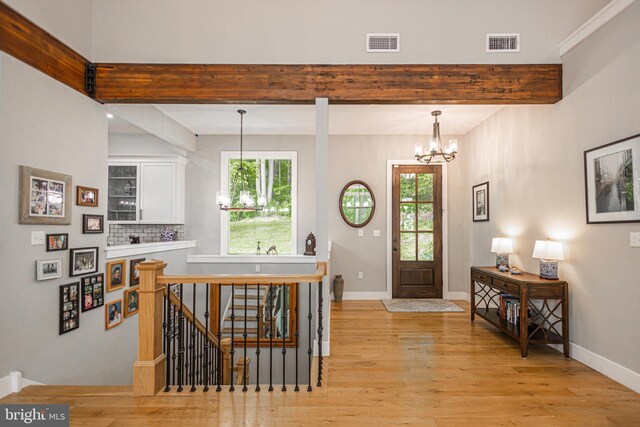 foyer featuring light wood-type flooring, a healthy amount of sunlight, and a notable chandelier