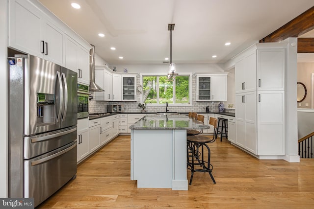 kitchen with pendant lighting, a kitchen island, white cabinetry, a kitchen breakfast bar, and stainless steel appliances