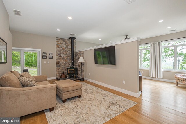 living room with a wood stove and light hardwood / wood-style flooring