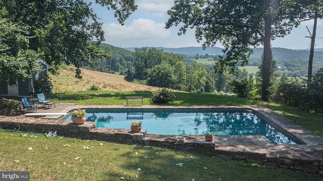 view of swimming pool with a mountain view, a patio area, and a lawn