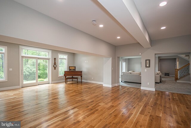 unfurnished living room with beam ceiling and light hardwood / wood-style flooring