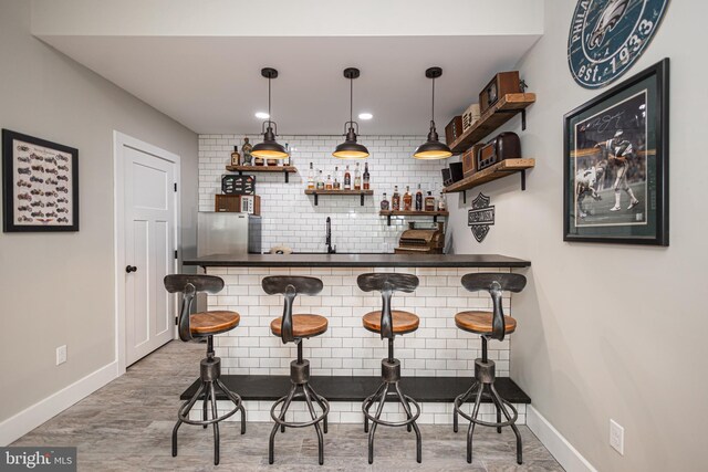 bar with decorative backsplash, sink, and hanging light fixtures