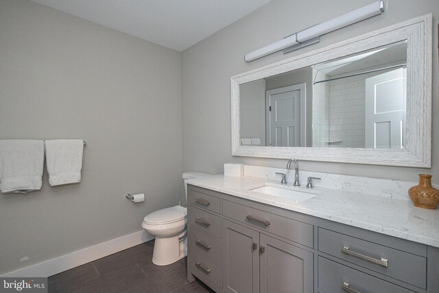 bathroom featuring toilet, vanity, and a shower