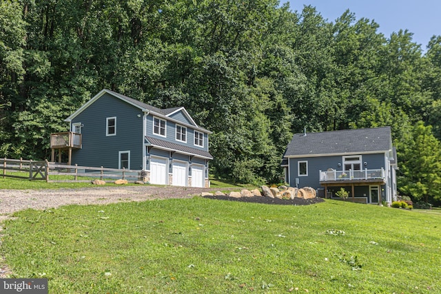 front facade featuring a front yard, a wooden deck, and a garage