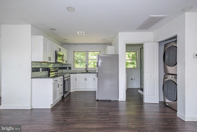 kitchen featuring white cabinetry, stacked washer and clothes dryer, appliances with stainless steel finishes, dark hardwood / wood-style floors, and sink